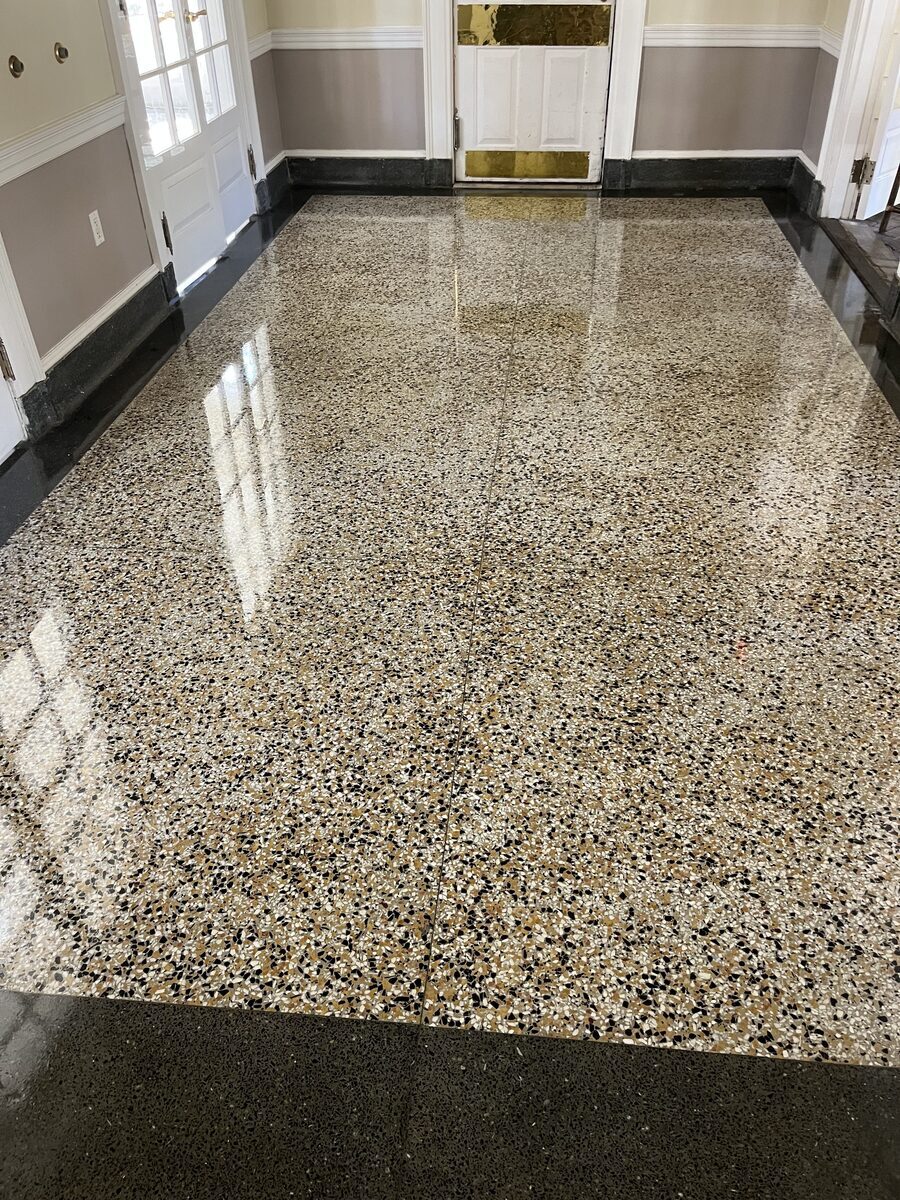 Detailed close-up of terrazzo floor with high-gloss finish showing chip aggregate and mirror-quality reflections — System4 of North Florida commercial floor care crew work